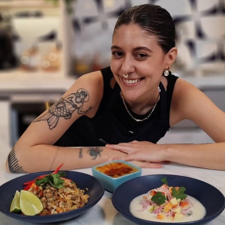 Foto de Luísa Motta usando regata preta em frente a dois pratos de comida vegana