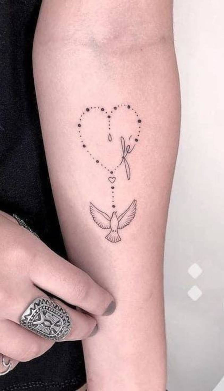 tatuagem feminina de fé, com terço e Espírito Santo