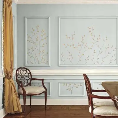 Sala com mesa e cadeiras, cortina mostarda, parede verde-clara com papel de parede dentro da moldura 