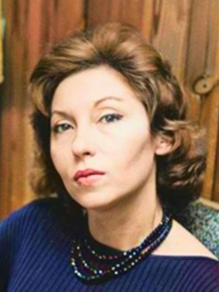 Foto de Clarice Lispector sentada em fundo de madeira