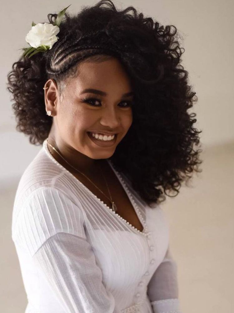 Noiva de pele negra com trannça nagô na lateral, cachos e flor 
