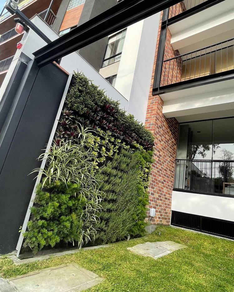 Jardim vertical decorando fachada de prédio com parede de tijolinhos