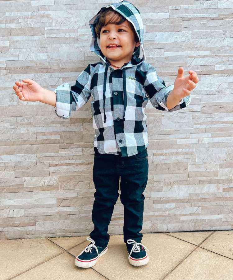 Menino com camisa xadrez preto e branca com touca e calça preta