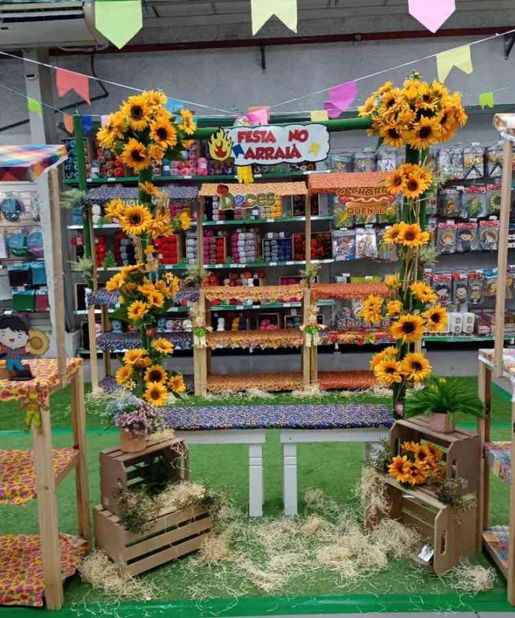 Ideia de vitrine com painel de girassóis e banco, além de caixotes, com tema São João