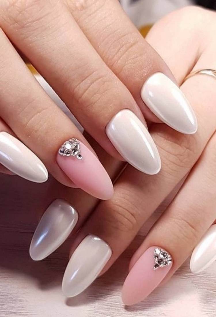 Unhas brancas cintilantes em formato almond com rosa fosco no anelar, que também conta com pedrarias 