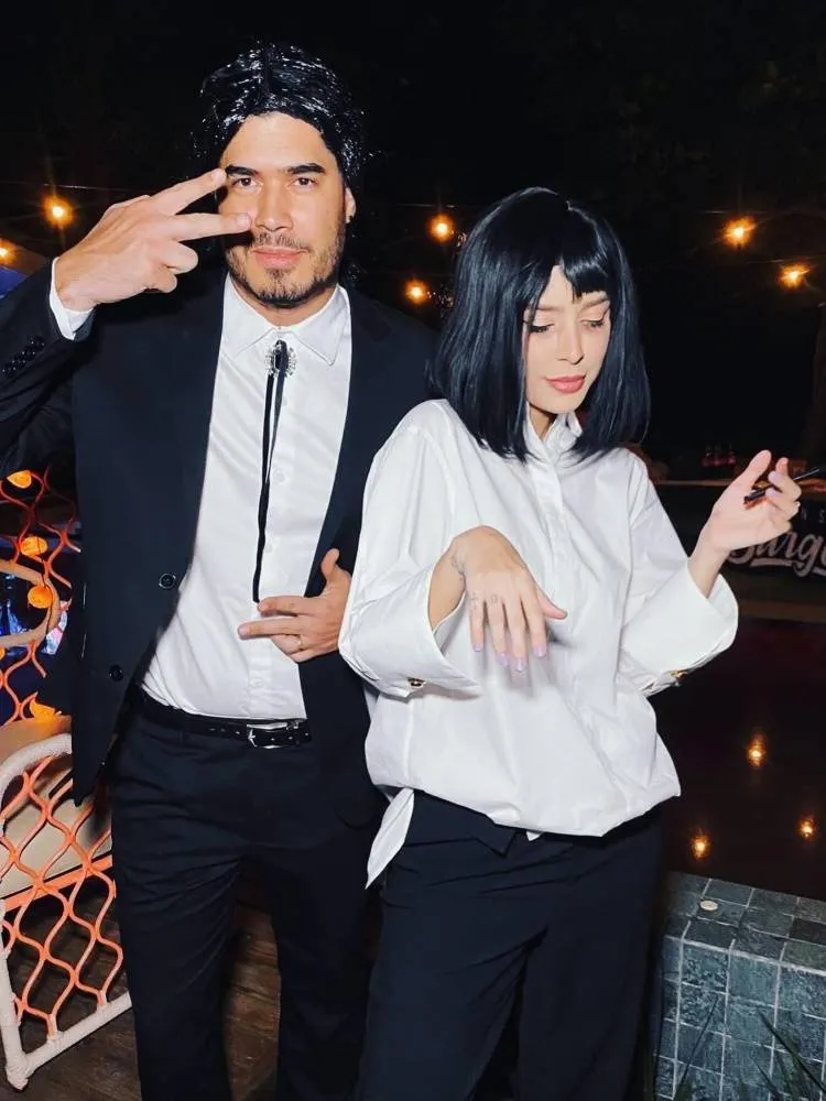 Casal de influenciadores Rica de Marré e Adrão Meron fantasiados de Vincente Veja e Mia Wallace do filme "Pulp Fiction" para o Halloween. Ele sua cabelo preto, camisa branca e terno. Ela usa cabelo preto curto, camisa branca e calça preta 
