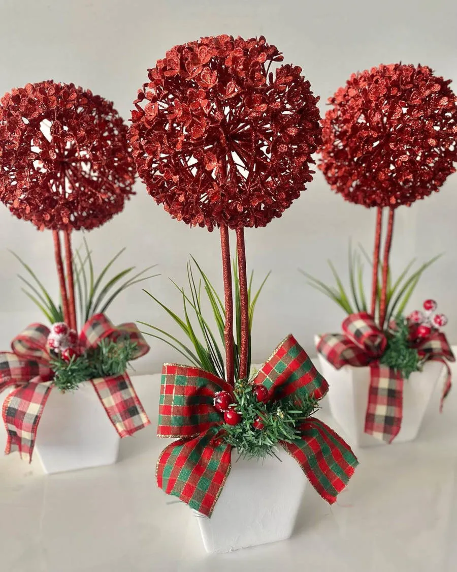 TrÊs vasos brancos com flores vermelhas.
