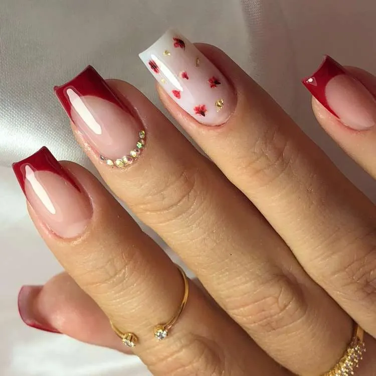 Nail art com vermelho, folha dourada, florzinhas e pedraria