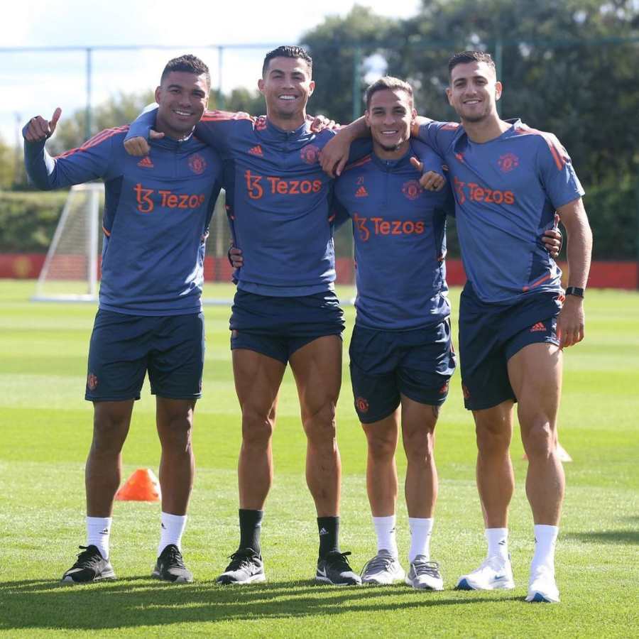 Imagem de futebolistas Casemiro, Cristiano Ronaldo, Antony e Diogo Dalot em campo de futebol.