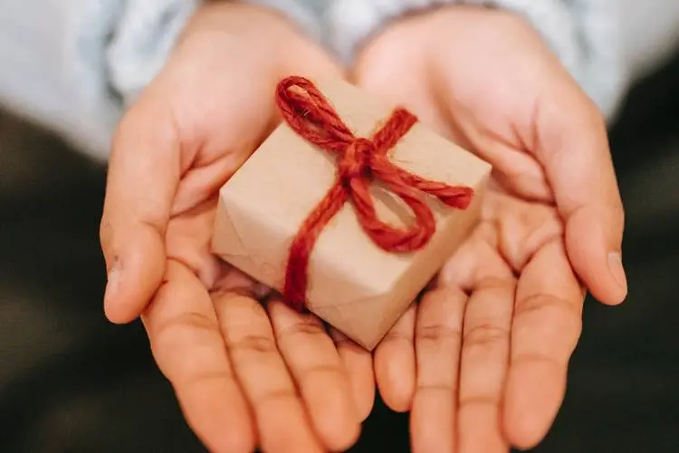 Foto de pessoa segurando um pequeno presente - amigo secreto. 