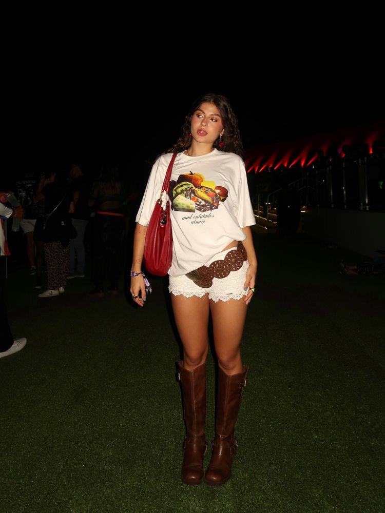 Malufca usando blusa estampada de frutas, shorts curtinho de renda, cinto maximalista, bota biker 