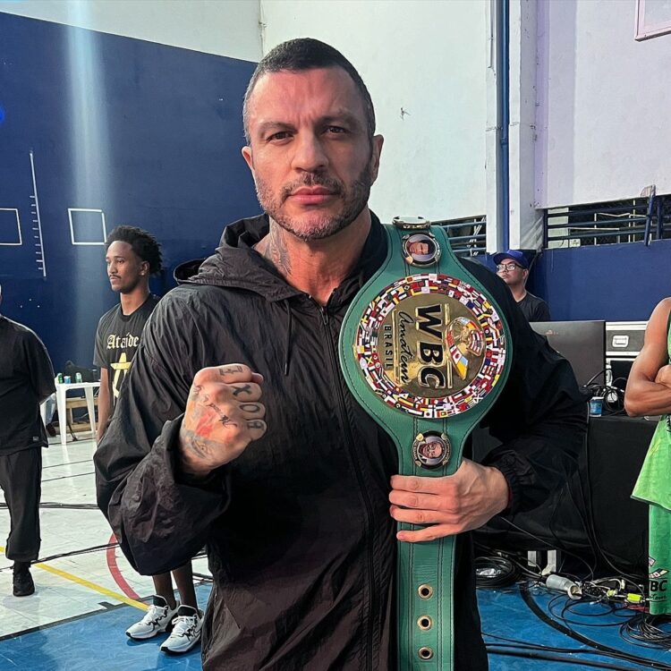 Kleber Bambam de corta-vento preto segurando cinturão do WBC