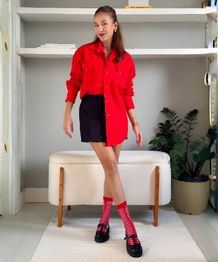 Mulher usando camisa vermelha, short preto, meia longa estampada e sapato boneca