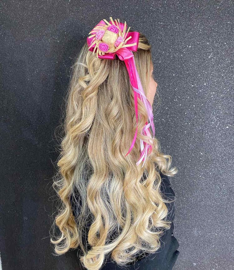 Mini chapéu com rosas e fitas rosa e roxa, em cabelo loiro.