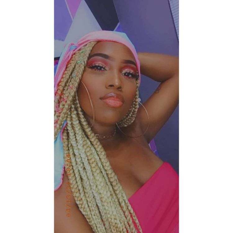 Leidy Elin de tranças loiras, lenço no cabelo e cropped rosa tomara que caia. 