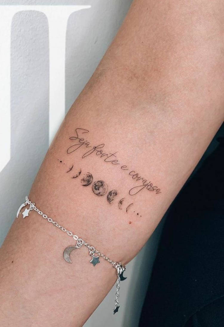 Tatuagem com as fases da lua e frase "seja forte e corajosa"
