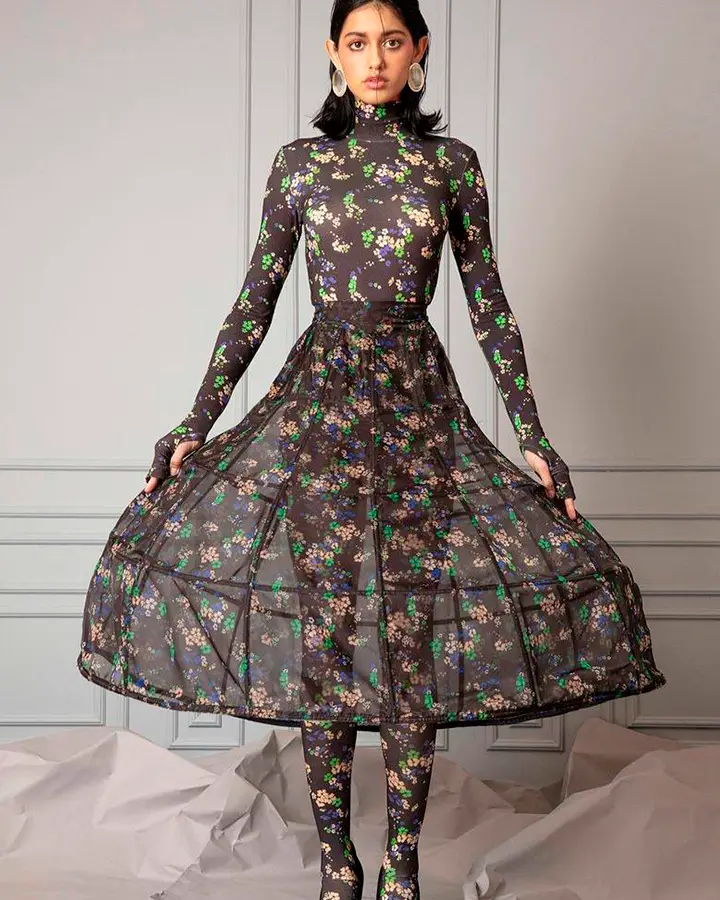 Modelo veste blusa, saia e meia calça com estampa preta cheia de flores.