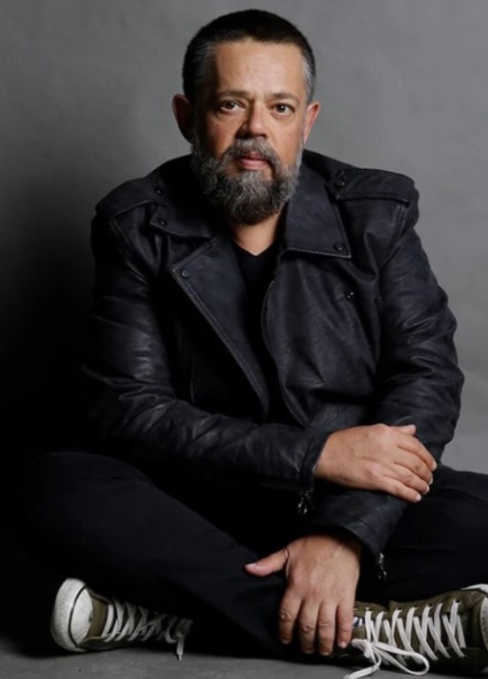 O estilista Vitor Zerbinatto posando sentado no chão.