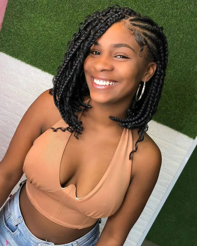 Mulher com trança nagô lateral e box braids preto, cabelo médio até os ombros