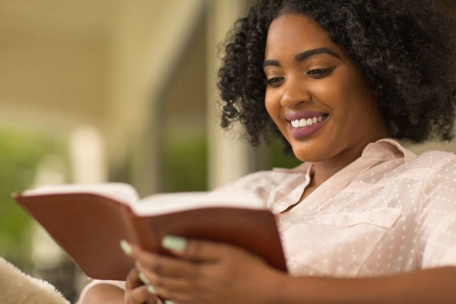 Mulher sorrindo enquanto lê um livro sobre a participação feminina na política.
