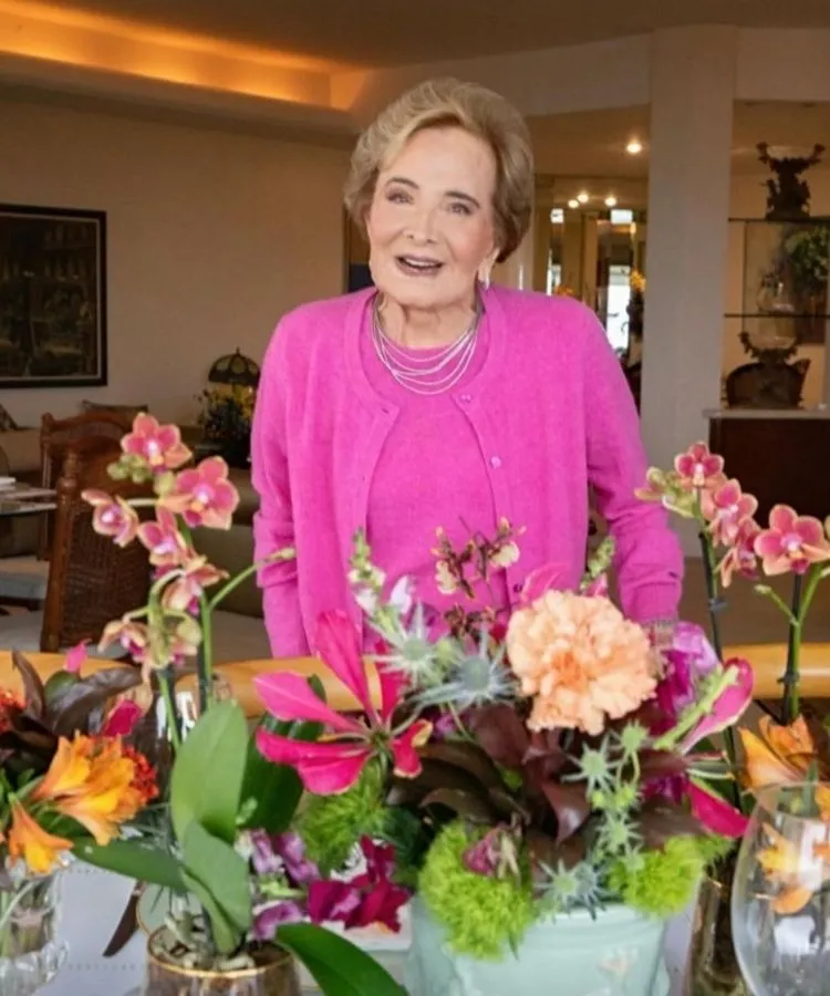 Atriz Glória Menezes em frente a mesa com flores