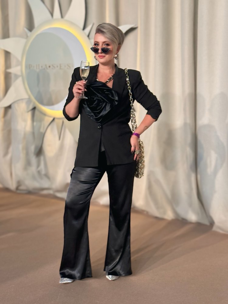 Andréia Almeida de macacão preto com flor 3D no evento da Charth