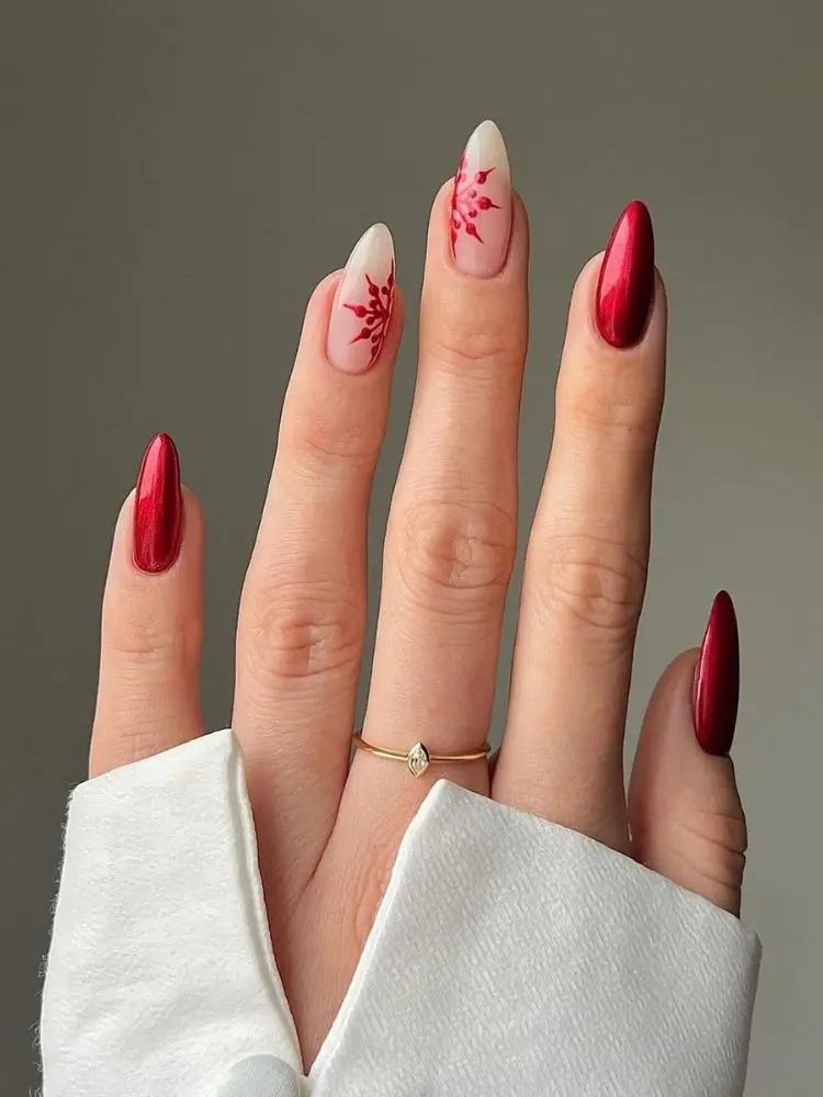 mão com unhas almond, sendo 3 delas com vermelho e duas transparentes com metade de floco de neve vermelho
