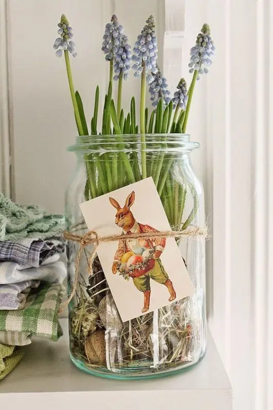  jarro de vidro com flores lilás decorado com barbante e cartão de coelho