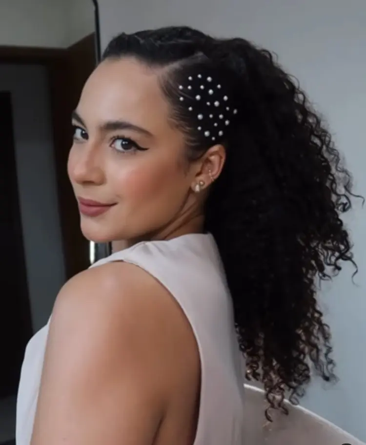Mulher de pele morena usando cabelo semi preso e pérolas