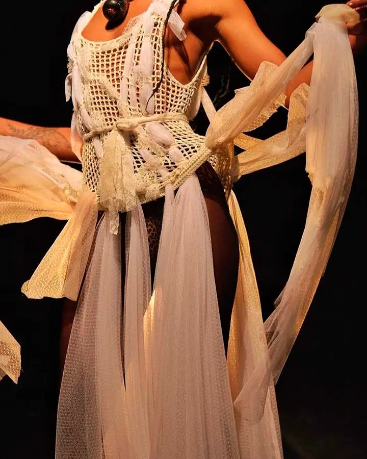 Vestido branco feito de crochê, nós e tecidos esvoaçantes.