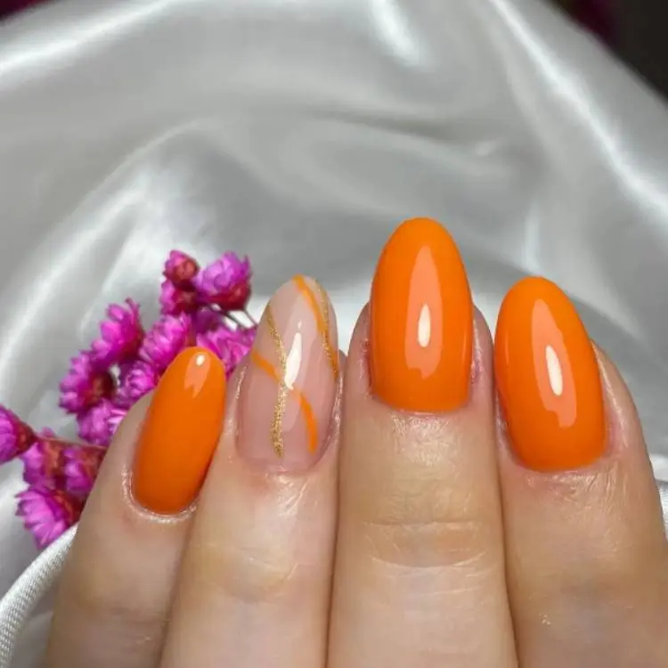 unhas laranjas com traços dourados