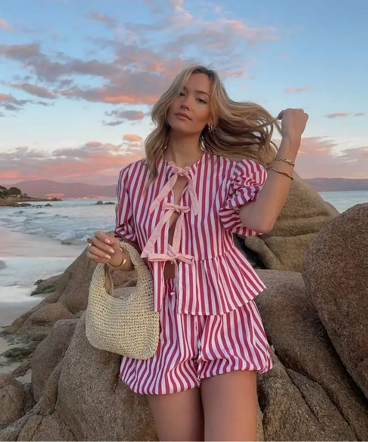 Mulher loira usando conjunto listrado rosa e vermelho para look de Natal