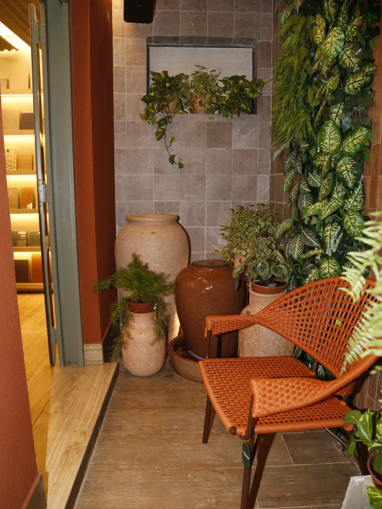 Varanda com azulejo cinza, cadeira marrom, vasos bege e jardim vertical, ideia de decoração barata