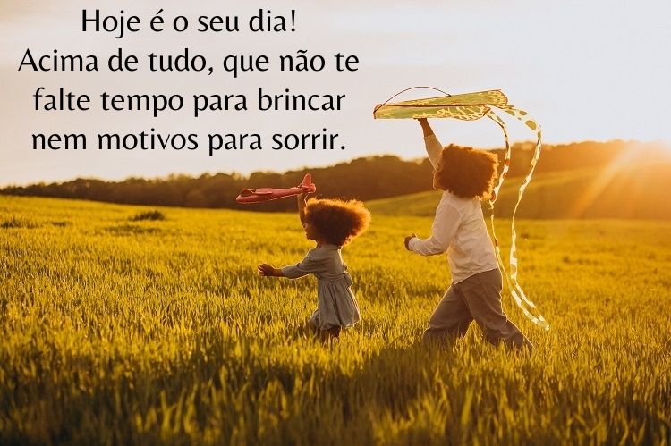Foto de duas crianças brincando de pipa em gramado e frase "Hoje é o seu dia! Acima de tudo, que não te falte tempo para brincar nem motivos para sorrir."