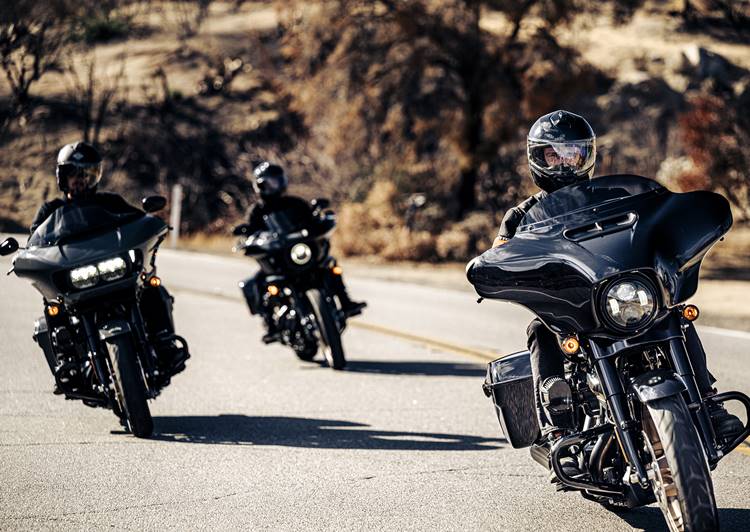 Pessoas pilotando motos da Harley-Davidson do Brasil em pista asfaltada. Foto de pessoas pilotando motos.