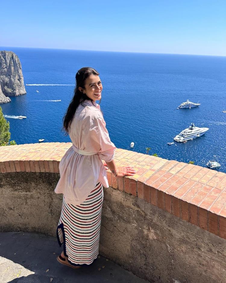 mulher apoiada em mureta olhando para paisagem do mar