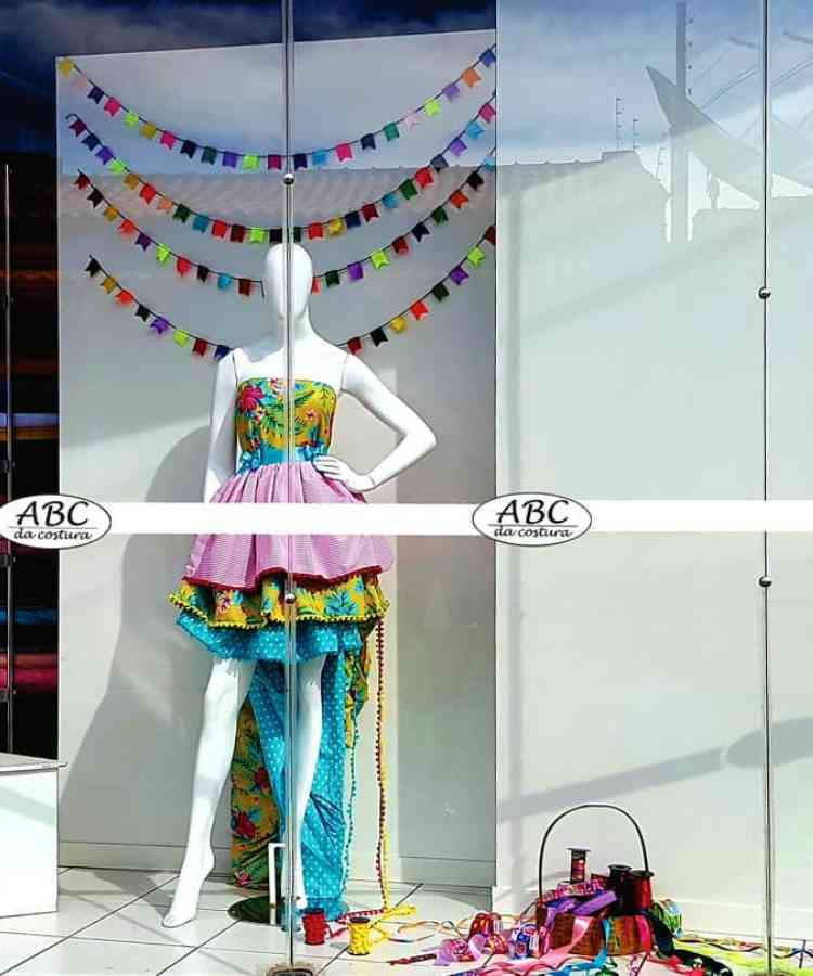Vitrine de loja de costuma com manequim usando vestido de festa junina e bandeirinhas penduradas