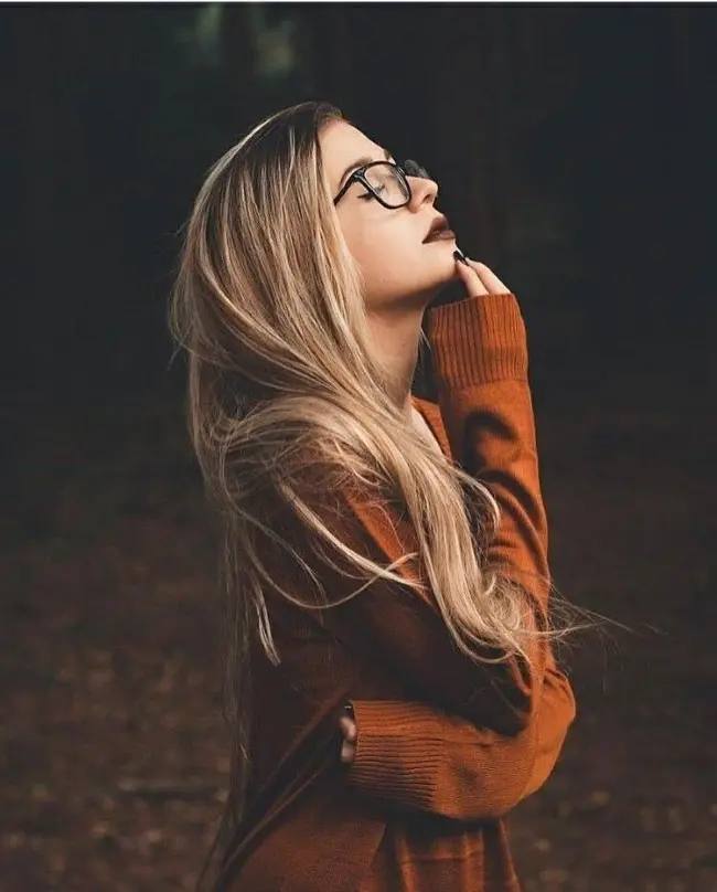 Frase para foto pensativa mulher branca loira usa óculos de grau com moletom caramelo, batom marron e unhas pretas Frase para foto pensativa mulher branca