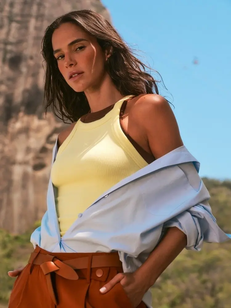 Foto de Bruna Marquezine de regata amarela, camisa azul e calça marrom na campanha de verão 26 da Hering