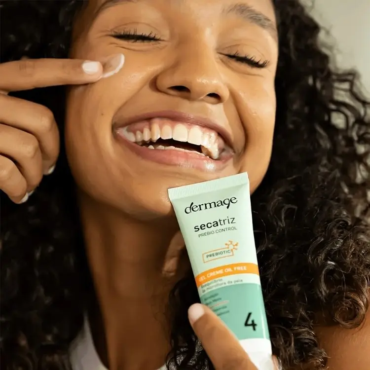 Mulher de pele negra segurando e aplicando Secatriz Prebio Control, Dermage