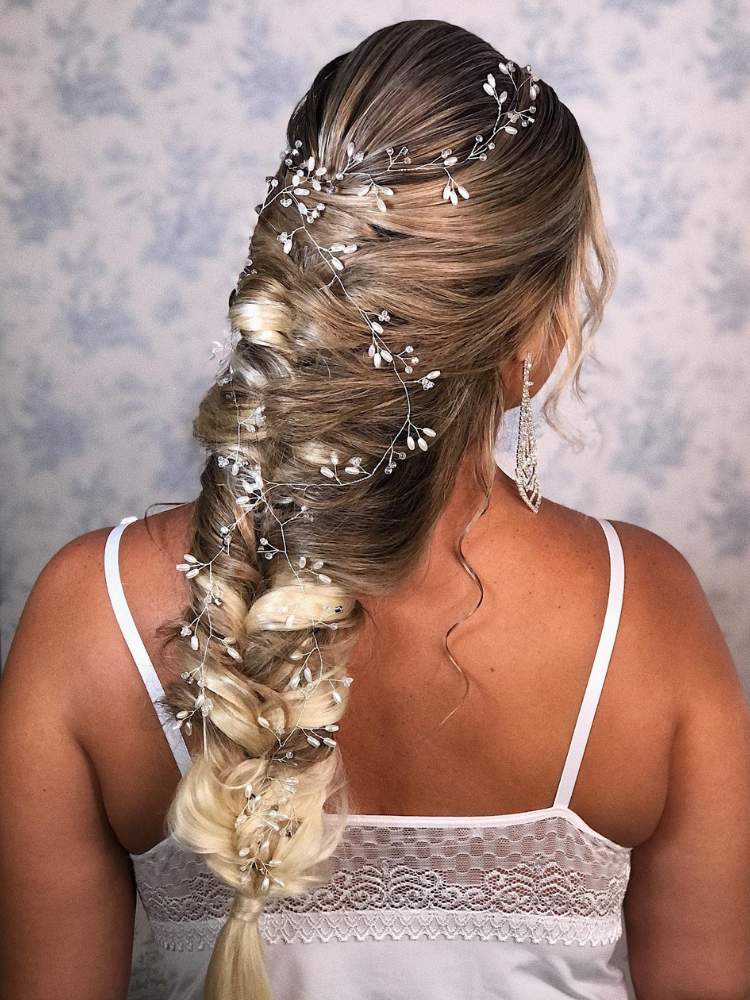 Mulher de pele clara de costas com trança diferente no cabelo e  acessórios prateados ao longo dos fios