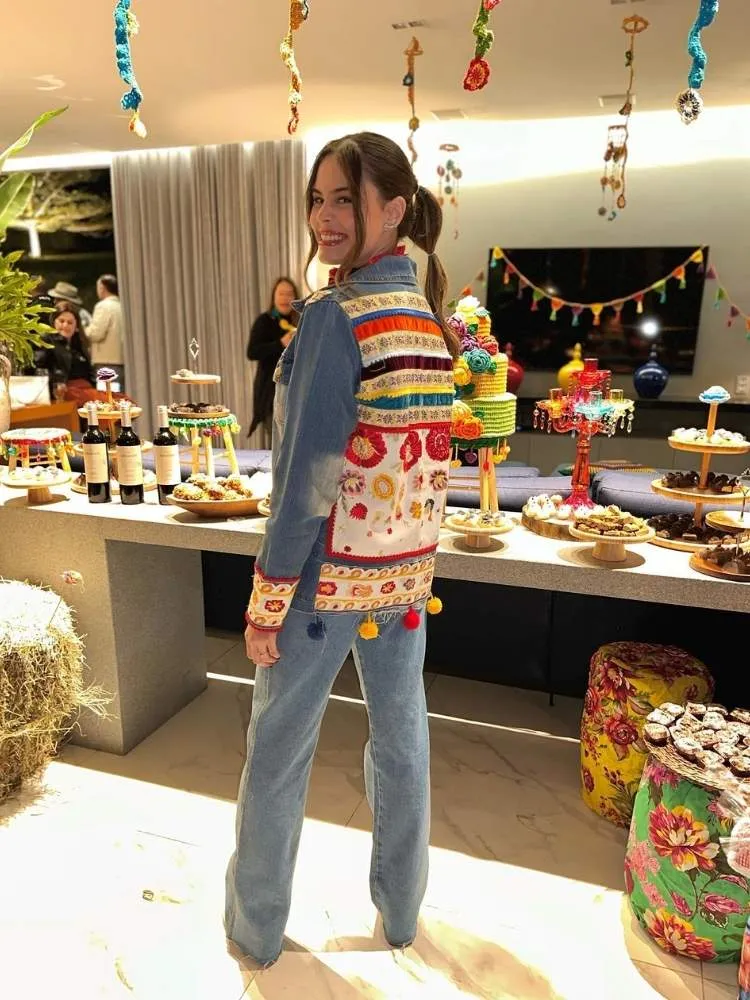 Mulher de pele clara em festa junina indoor com look all jeans com retalhos nas costas da jaqueta 