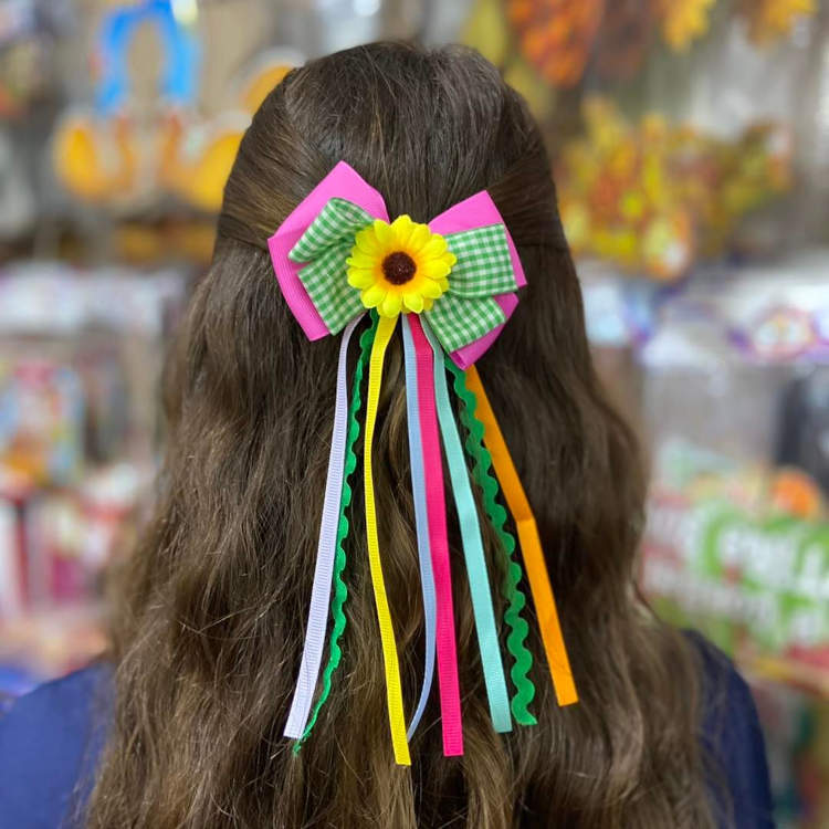 Laço em cabelo castanho com fitas coloridas e girassol