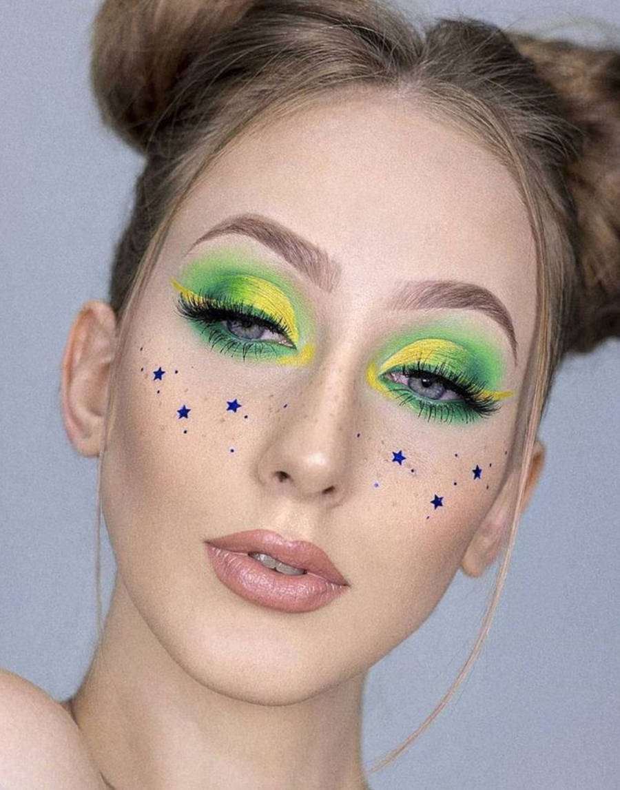 Foto de mulher com glitter de estrelinhas no rosto simulando sardas: Maquiagem para copa