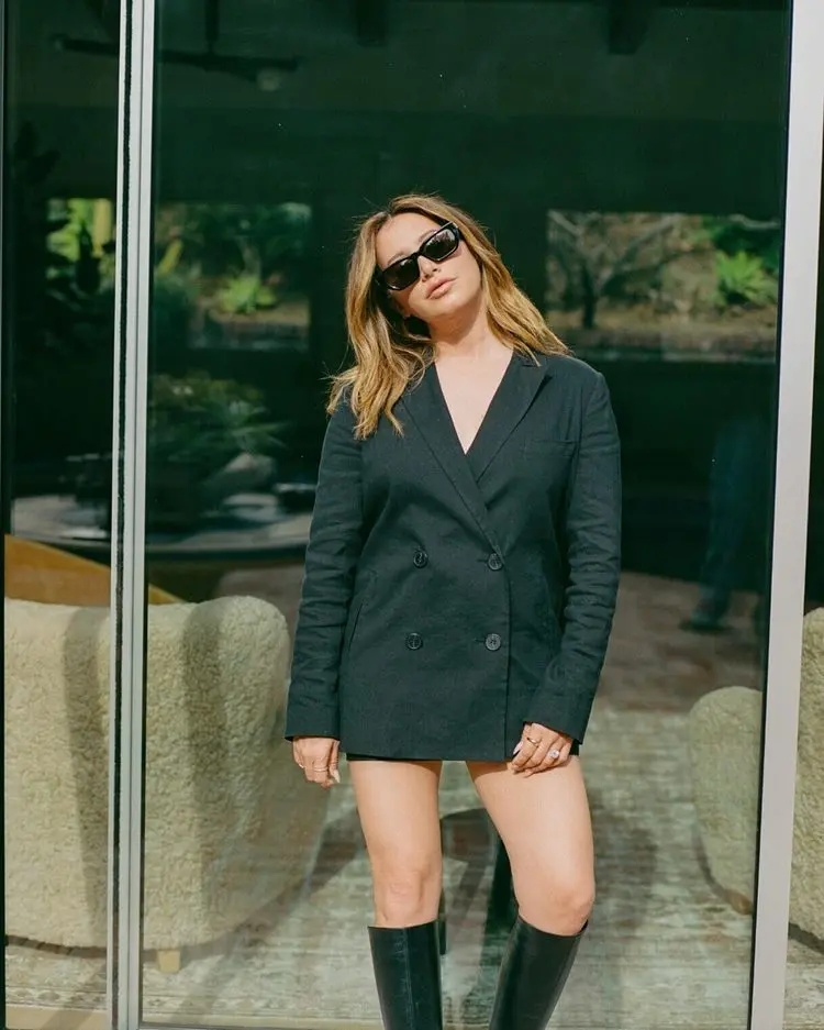 Atris Ashley Tisdale de The Suite Life of Zack & Cody grávida em 2024, usando blazer preto e bota de cano longo