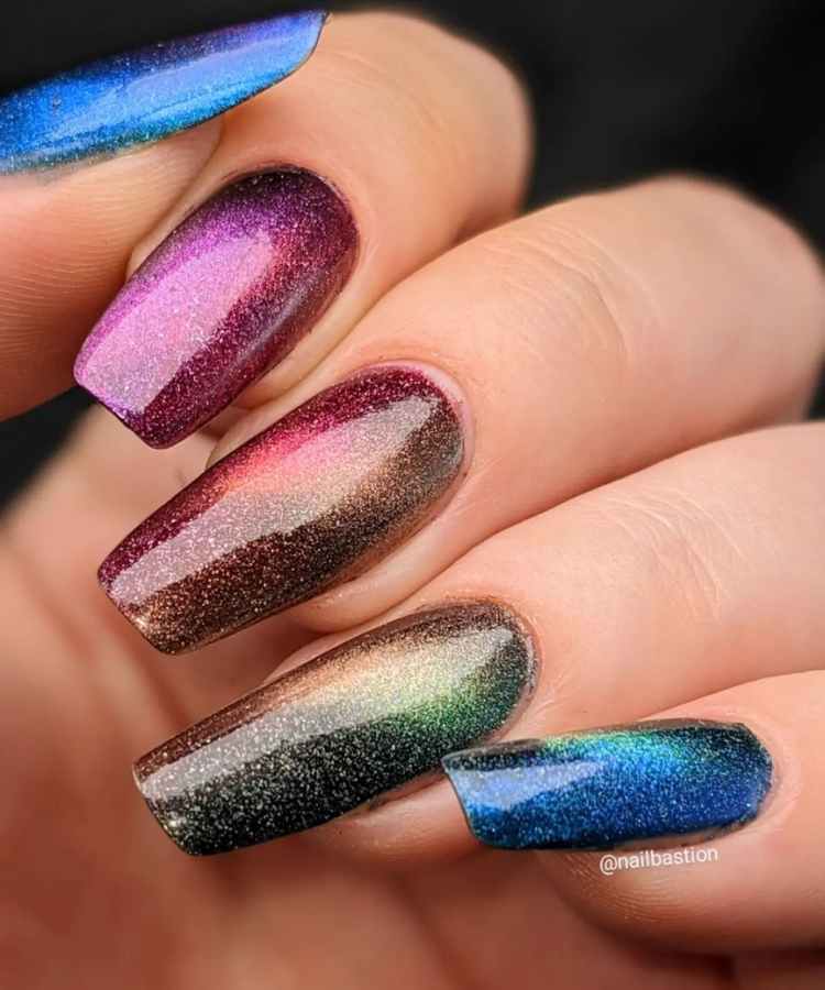 Pessoa de pele clara com unhas quadradas grandes e esmalte glitter magnético de diversas cores