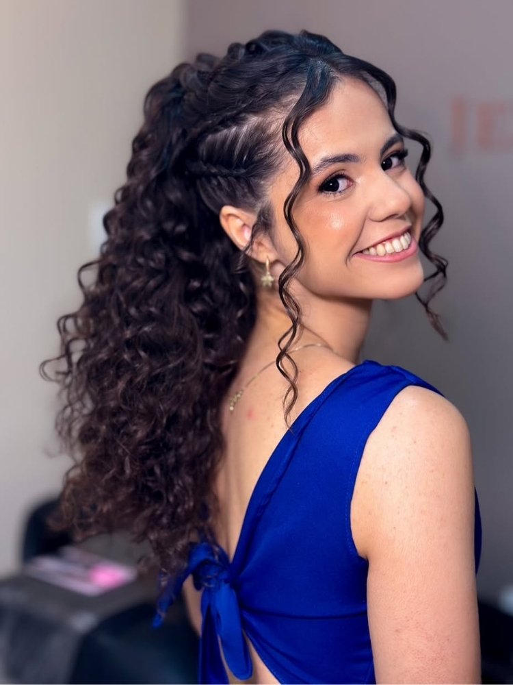 Foto de mulher de cabelos cacheados longos usando penteado com tranças laterais