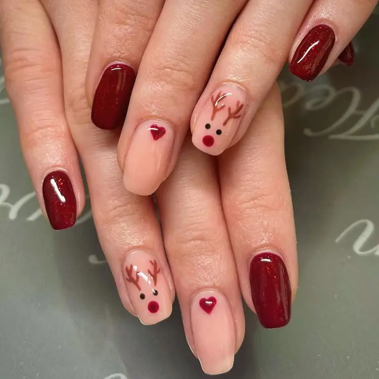 mãos com unhas de nail art de rena, coração e vermelhas