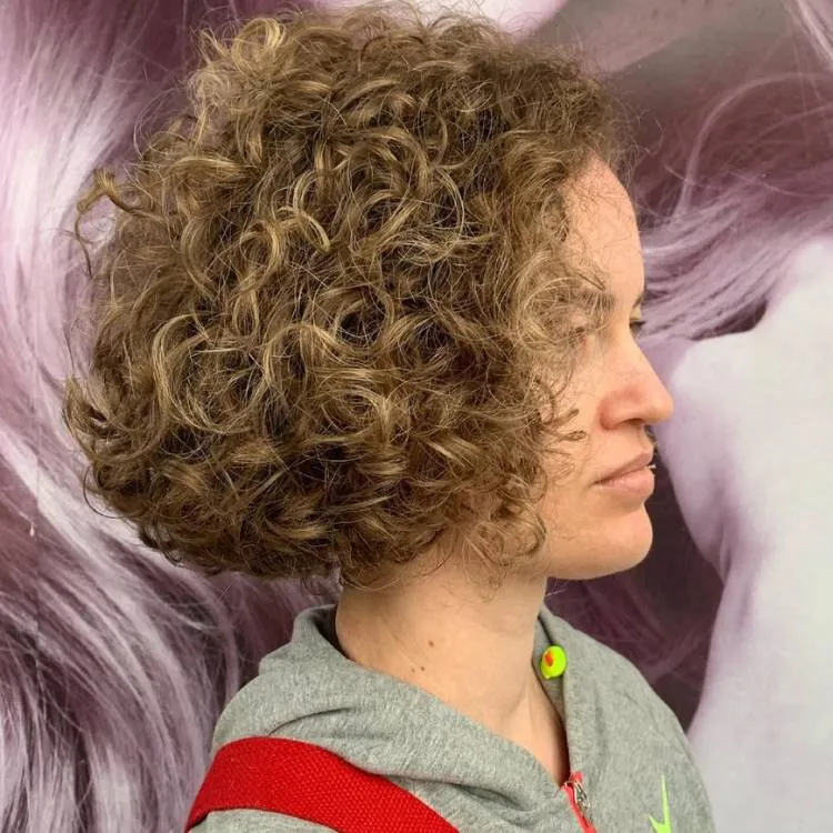 Mulher de pele clara de lado com cabelo chanel cacheado loiro