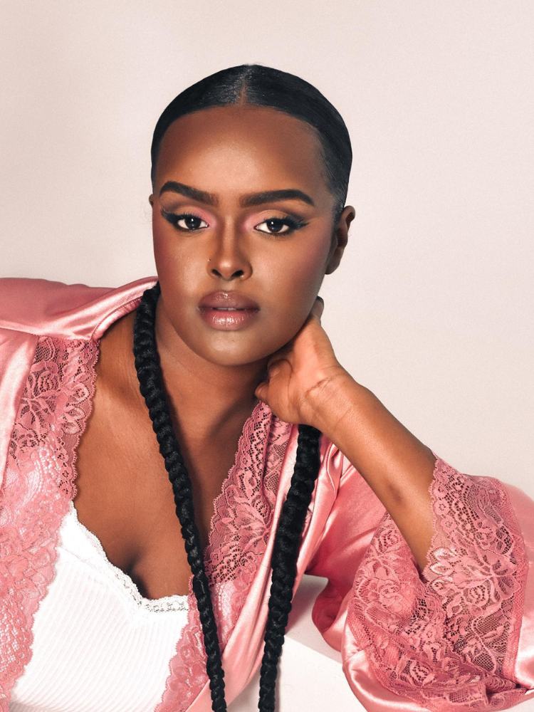 Mulher de pele negra com bombshell makeup, com delineado esfumado, cílios postiços no canto e boca contornada 